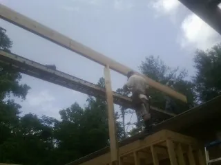 Carpenter setting a ridge beam over a new addition frame — Ice Dam Removal by Roofing Brothers in Mattituck