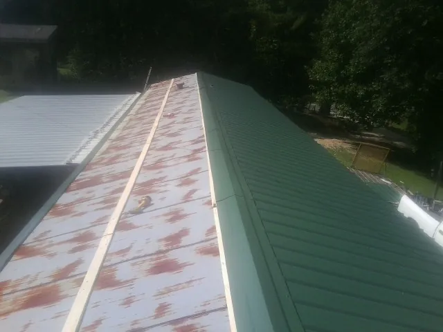 Old rusted panels beside newly installed green metal roofing — Wind Damage Roof Repair by Roofing Brothers in Mattituck