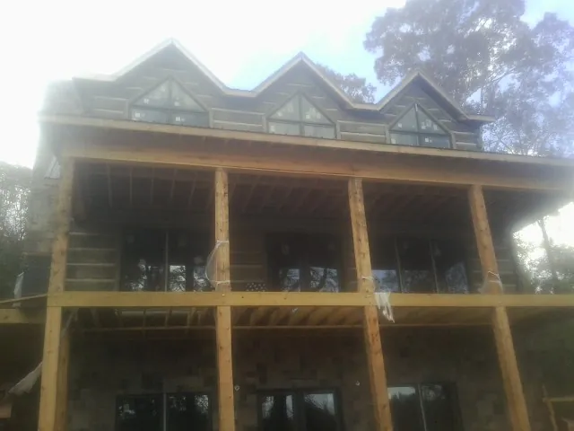 Dormers and porch framing on a large log home under construction — Roof Coating work by our crew in Mattituck