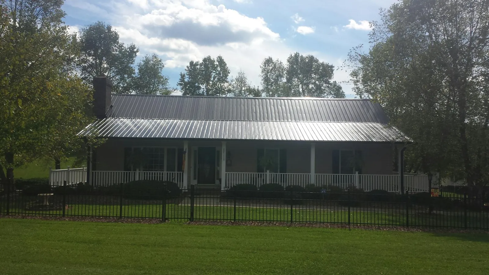 Gray metal roof on a brick ranch with a full width front porch — Gutter Guard Installation work by our crew in Mattituck