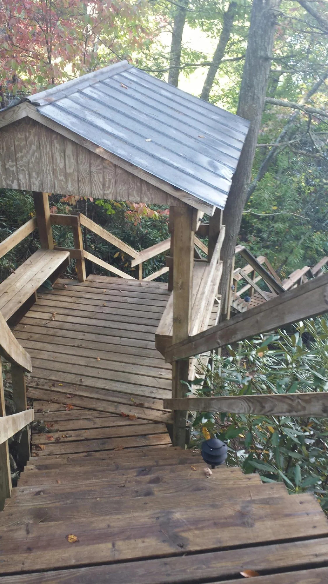 Metal roofed shelter over wooden steps on a wooded walkway — Skylight Repair & Installation work by our crew in Mattituck
