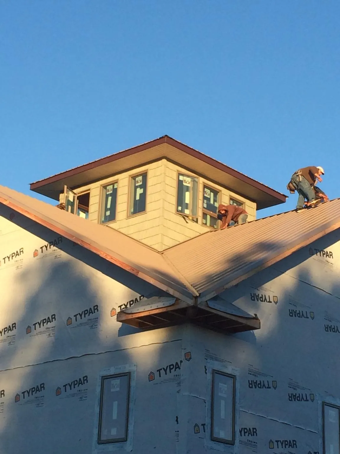 Roofers working around a rooftop cupola on a new metal roof at sunset — Roof Waterproofing in Mattituck by Roofing Brothers